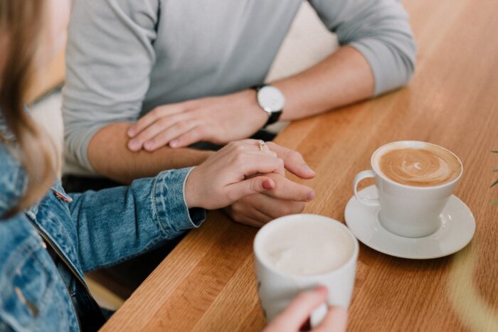 man and woman at a coffee shop holding hands